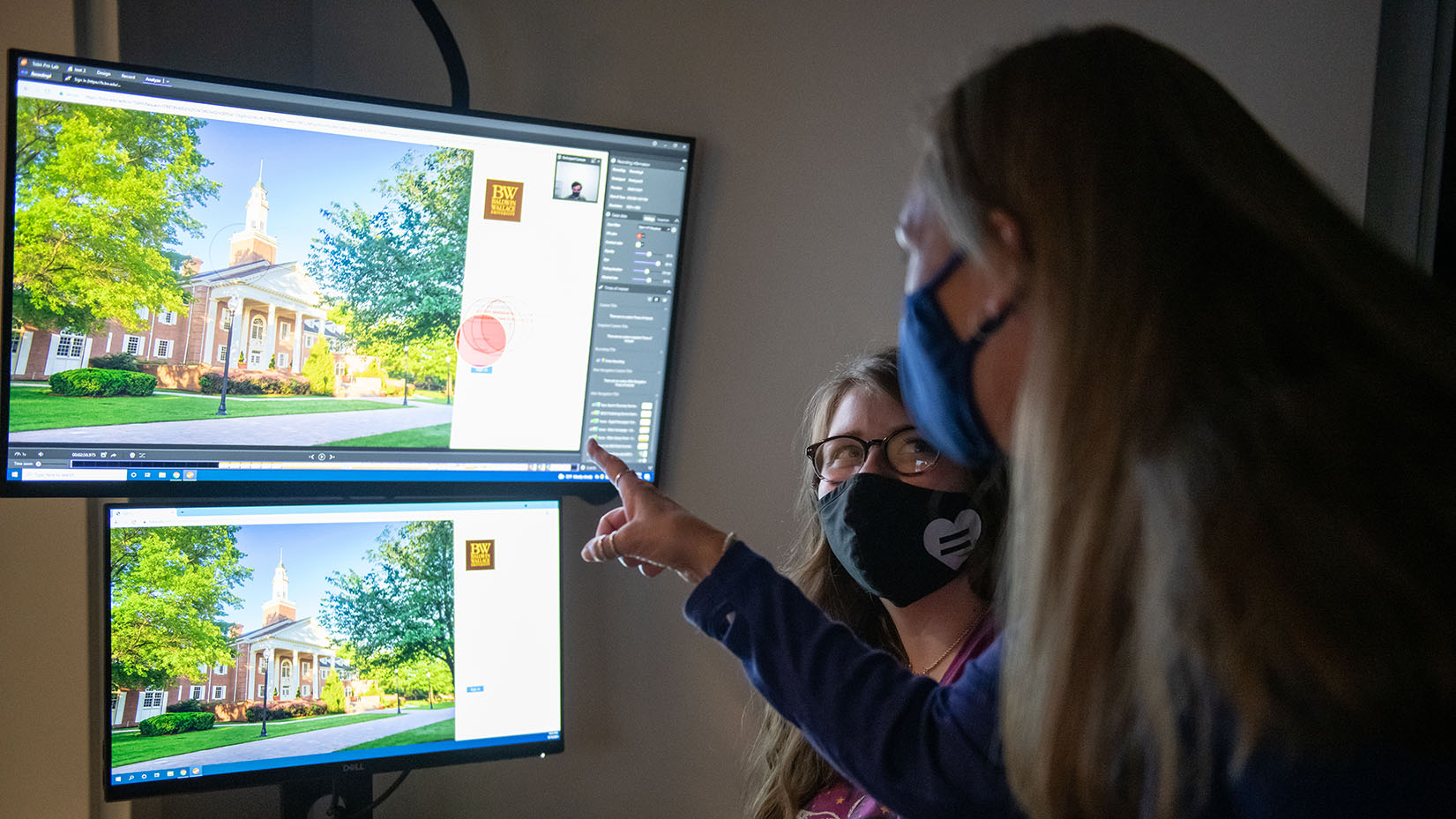 a student and a professor pointing at two monitors